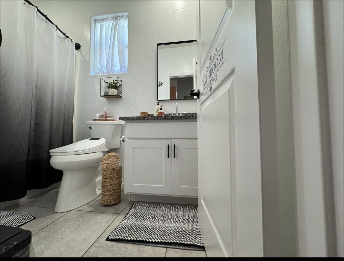 The guest bathroom with a white vanity, mirror and shower